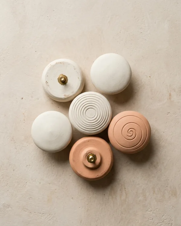 Cluster of round clay drawer knobs, two turned over to show brass screws