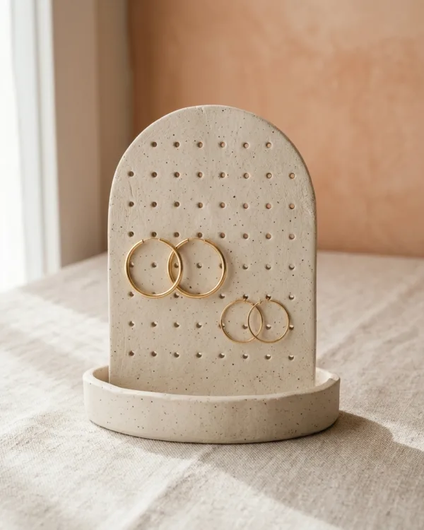 Arched clay earring stand with punched holes holding gold hoop earrings