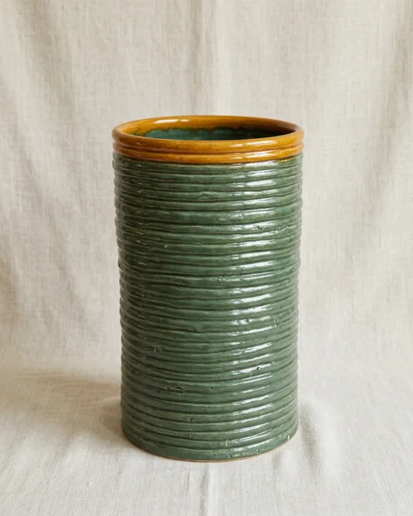 A tall coil-built sage green ceramic garden planter