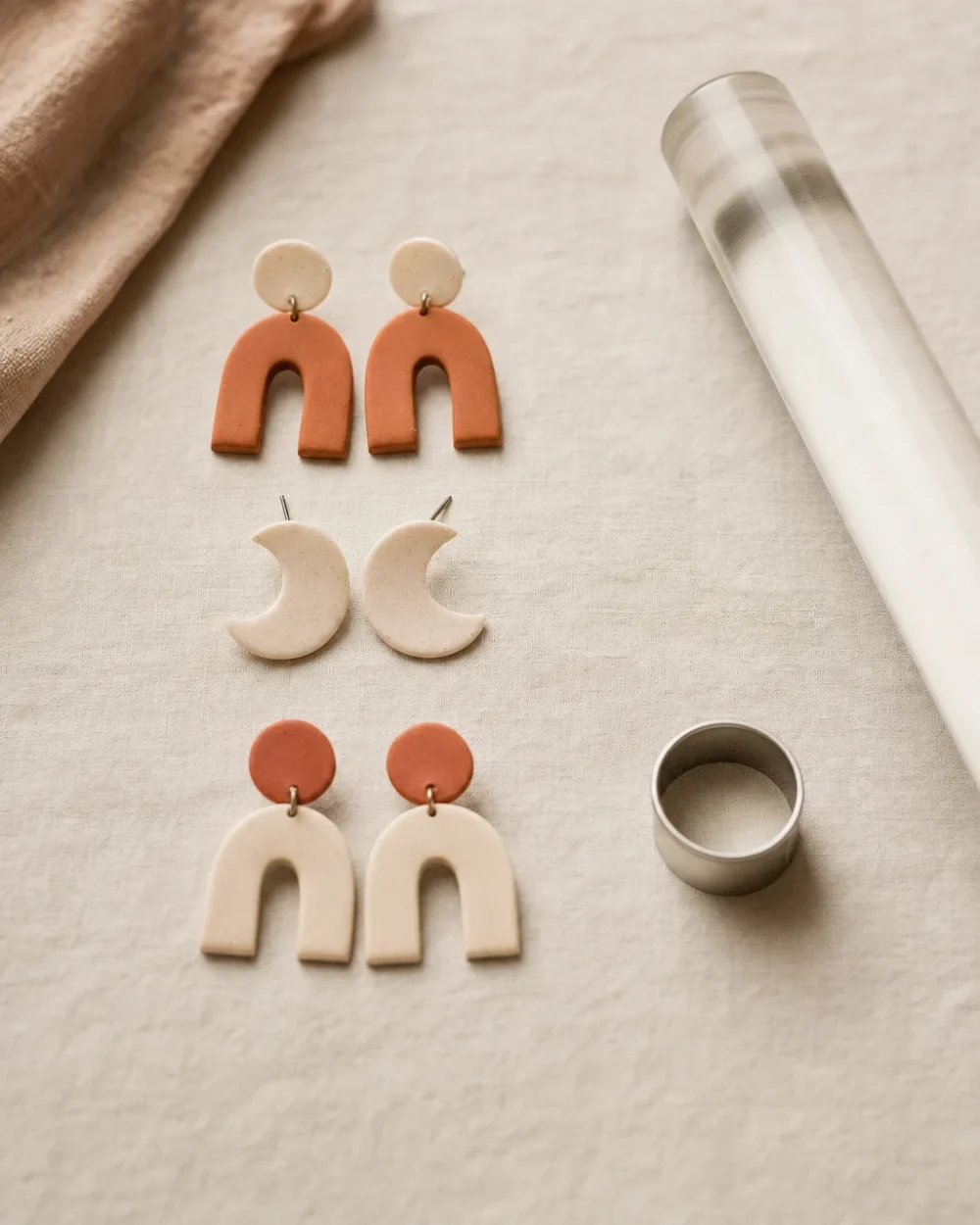 Three pairs of handmade polymer clay stud earrings in terracotta and bone on linen